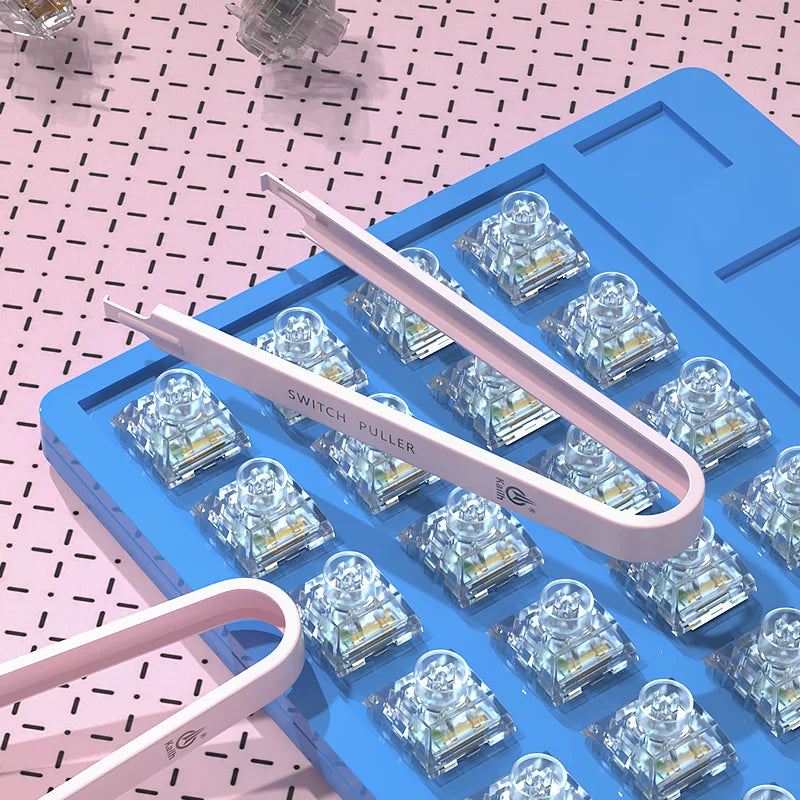 Blue switch puller tool with clear switches on a pink and black patterned surface