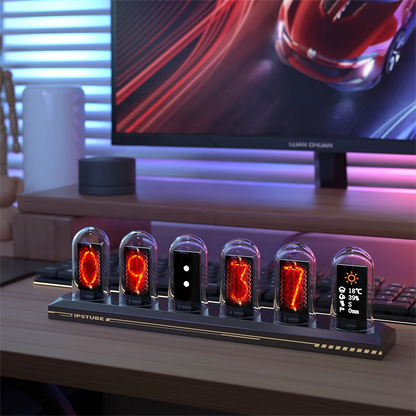 Digital clock with LED display on a desk in front of a computer monitor.