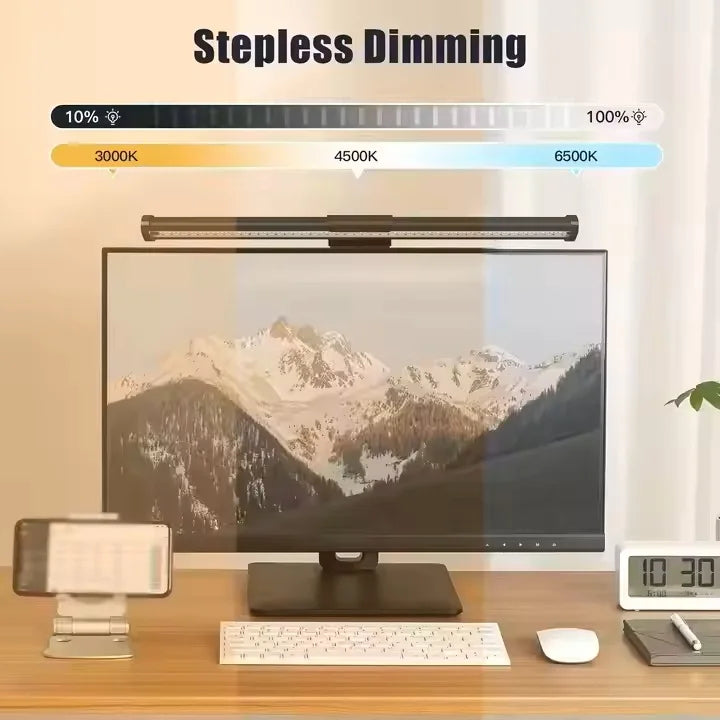 Desk setup with a monitor displaying mountain scenery, a lamp labeled 'Stepless Dimming', and various office items.