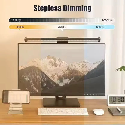 Desk setup with a monitor displaying mountain scenery, a lamp labeled 'Stepless Dimming', and various office items.