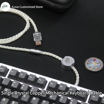 Single Crystal Copper Mechanical Keyboard Cable on a black surface with keyboard in the foreground