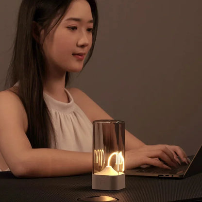 Woman using a laptop with a lit candle on a table