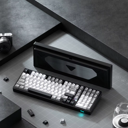 Mechanical keyboard on a gray surface with a black box in the background