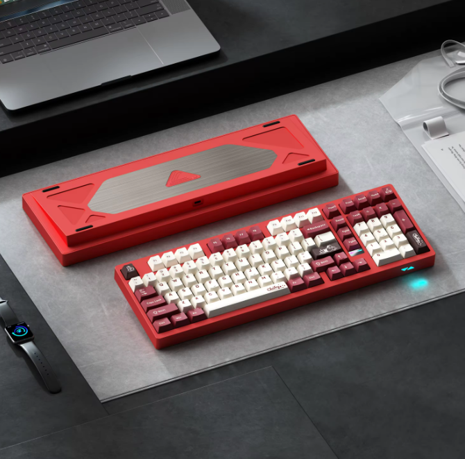 Red and white mechanical keyboard on a desk with a laptop in the background
