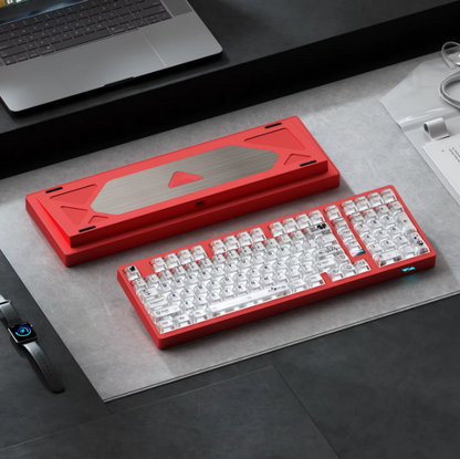 Red mechanical keyboard on a desk with a laptop and smartwatch in the background