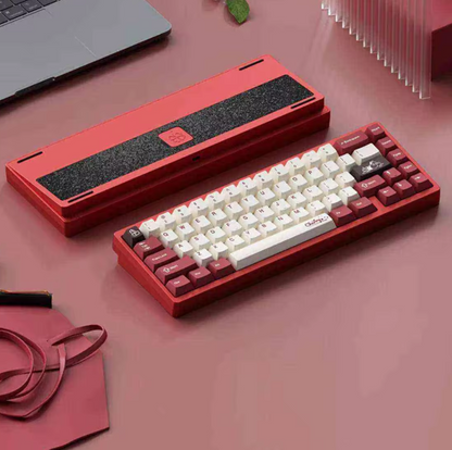 Red and white mechanical keyboard on a pink surface with a laptop in the background