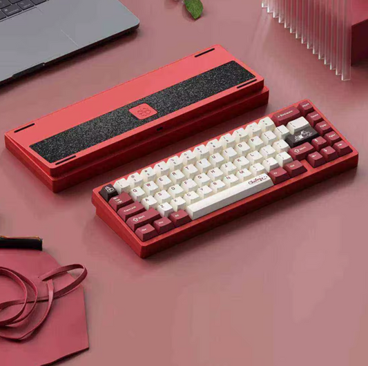 Red and white mechanical keyboard on a pink surface with a laptop in the background